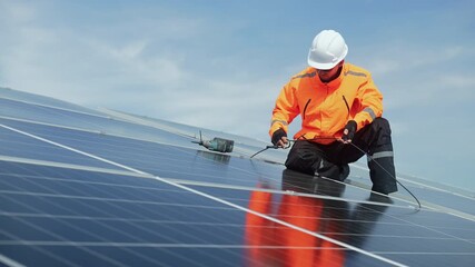 Technician installing solar panels on factory roof for green energy. A skilled technician in safety gear is working on a solar panel installation on rooftop. clean energy renewable power technology. - Powered by Adobe