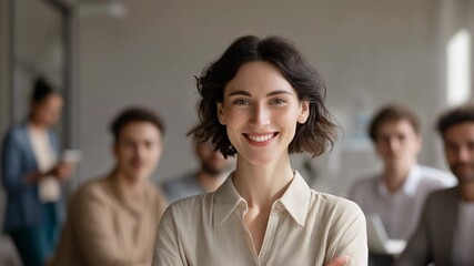 Confident young woman in a professional setting with colleagues in the background