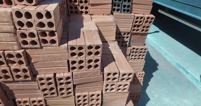 close up of a worker stacking red bricks.