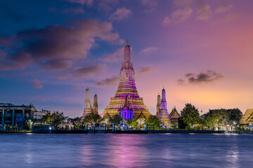 Naklejka premium 26 November 2025 Beautiful Sunset colours of Thai Temple Wat Arun on Chao Phraya River in BKK Bangkok Thailand. The magic colourful neon light display on the temple at sunset is magical.