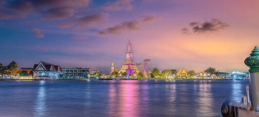 Naklejka premium 26 November 2025 Beautiful Sunset colours of Thai Temple Wat Arun on Chao Phraya River in BKK Bangkok Thailand. The magic colourful neon light display on the temple at sunset is magical.