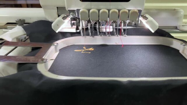 Industrial Embroidery Machine Stitching Logo on Black Fabric.