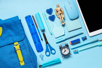 Composition with modern tablet computer and school supplies on blue background