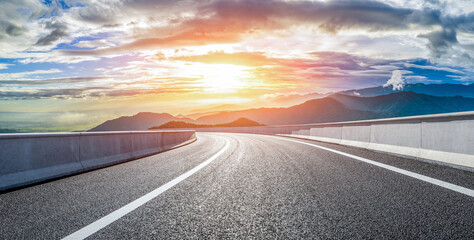 Fototapeta premium Empty asphalt road and beautiful mountain with dramatic clouds natural landscape at sunrise