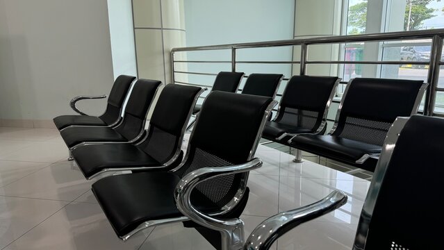 A row of empty, modern black tandem seating with chrome armrests in a bright - Powered by Adobe