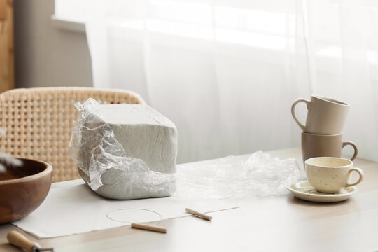 Wrapped clay block and pottery tools on table in home studio - Powered by Adobe