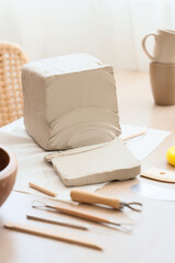Clay block and pottery tools on table in home studio, closeup