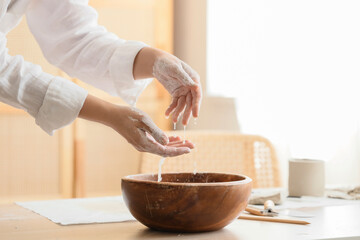Young female potter washing hands from clay in home studio, closeup
