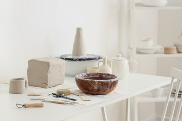 Clay block, bowl and pottery tools on table in home studio