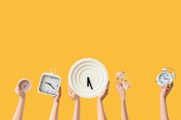 Female hands holding hourglass and different clocks on yellow background