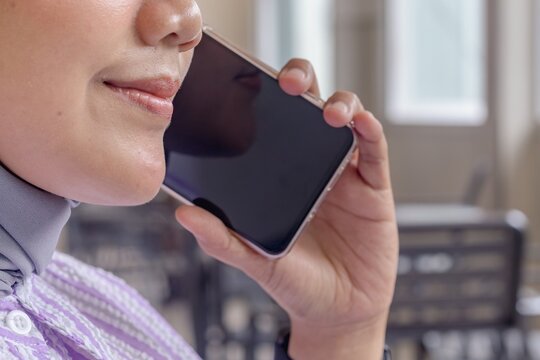 Close up shot of a young Asian woman making a call on mobile phone. Indoors. - Powered by Adobe