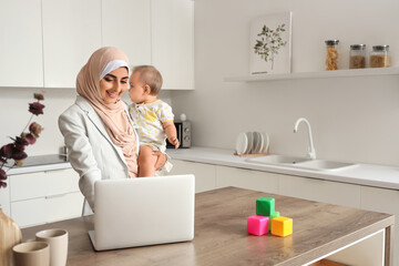 Young Muslim business mother with laptop and cute little baby working at home