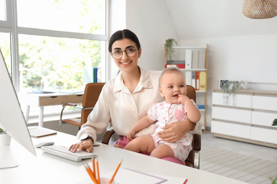 Young business mother with computer and cute little baby working at home