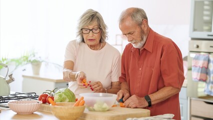 Happy retired couple preparing a vibrant salad filled with fresh vegetables in a sleek, modern kitchen, enjoying their time together