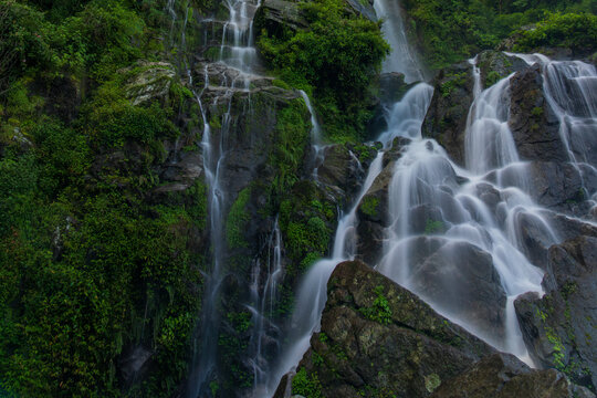Majestic mountain waterfalls cascading over rocky cliffs, surrounded by lush greener. A serene and powerful nature landscape perfect for travel, adventure, and scenic beauty themes.