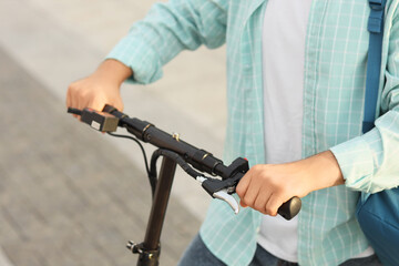 Young man riding electric scooter on city street, closeup