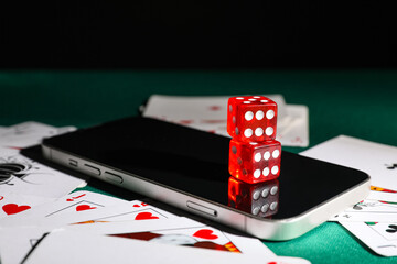 Obraz premium Mobile phone with playing cards and dices on green table, closeup