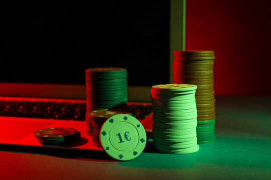 Laptop with poker chips on green table, closeup