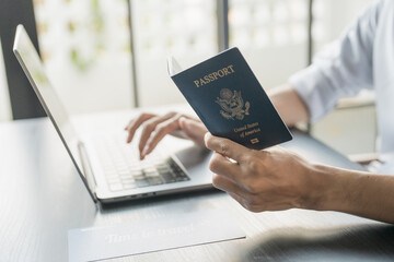 Hand Man Online booking and buying plane tickets using laptop phone and credit card Planning trip travel vacation with passport and ticket
