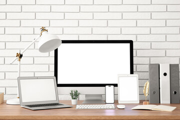 Fototapeta premium Modern home office workspace with blank screen computer, laptop, tablet, and smartphone on wooden desk