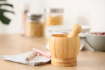 Wooden mortar with pestle on counter in kitchen, closeup