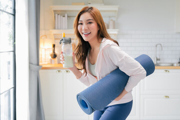 radiant fitness woman laughs joyfully in the sunshine while holding her water bottle and yoga mat at home, smiling brightly as she prepares for her energizing workout, staying hydrated and motivated