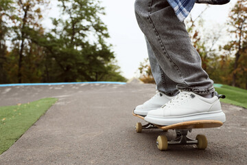Legs of young man with skateboard in park, closeup © Pixel-Shot