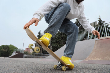 Legs of young man with skateboard in skatepark, closeup