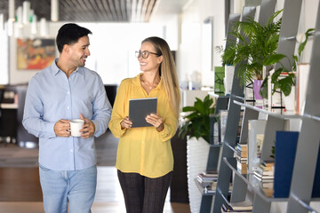 Couple of happy young office friends walking in co-working space
