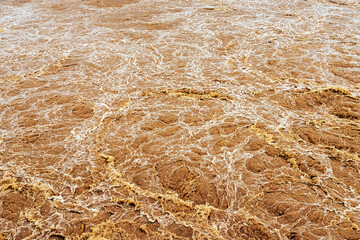 Smudged water flows profusely. River water flowing profusely. Flood waters rushing down river after...