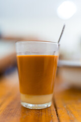 Hot orange tea with condensed milk on wood table