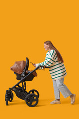 Young mother with her little baby in stroller using mobile phone on yellow background