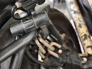 Close-up of a motorcycle security chain and lock attached to the frame. Shows details of metal links, padlock, and protective sleeve, ideal for illustrating security, protection, and anti-theft concep