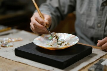 Artist painting intricate details on a decorative shell plate using a fine brush