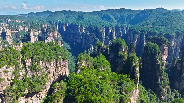 Aerial shot of majestic sandstone pillars and peaks with green forest in Zhangjiajie National Forest Park, Hunan Province, China.