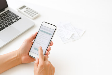 スマホでe-Taxオンライン確定申告をする日本人の手元とホワイトデスクのイメージ