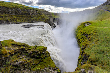 Gulfoss waterfall Water curtain cascading over green mossy cliff