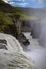 Gulfoss waterfall Water curtain cascading over green mossy cliff