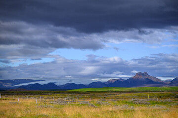 Dramatic sky over plains and distinctive mountain peak in Iceland