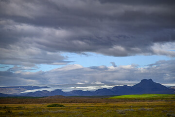 Dramatic sky over plains and distinctive mountain peak in Iceland