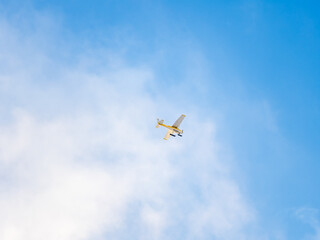 Small ultralight airplane with overhead wing and single propeller flying in sunset sky.