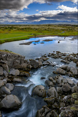 Thingvellir National Park Wide vista of volcanic mountains and grassy plains under blue sky