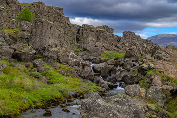 Thingvellir National Park drowning pool Clear pond and stream at the base of a towering tectonic cliff
