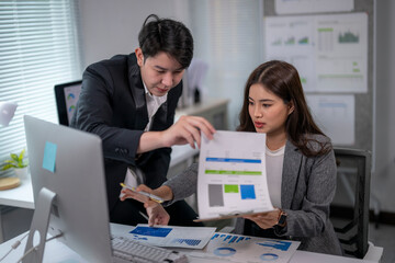 Asian businesspeople discussing and analyzing financial charts in office