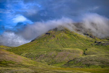 Cloud-shrouded volcanic mountain with basalt cliffs and mossy slopes in Iceland