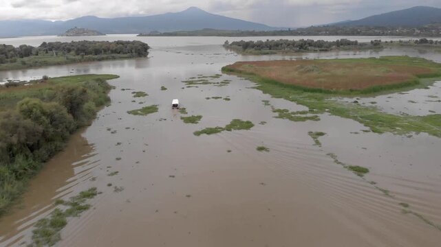 DRONE: DOLLY IN TILT DOWN SHOT OF PATZCUARO LAKE WITH A BOAT AND JANITZIO ISLAND
