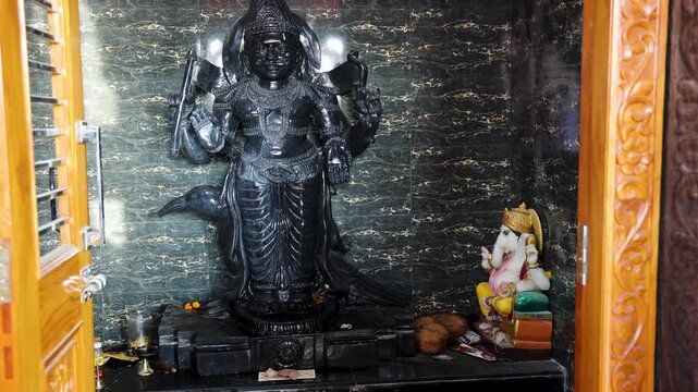 hindu shrine with shani dev statue and ganesha idol in marble alcove