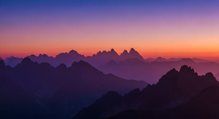 Panoramic mountain peaks during dawn with soft purple hues and orange horizon glow