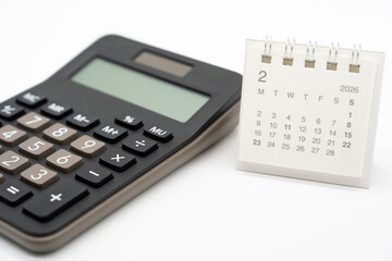 Desk calendar for February 2026 on white background. Calendar concept with 2026 FEB. Calculator and forecast for finances in 2026. Money, Budget, tax, investment and financial.