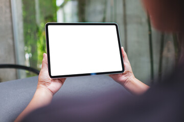 Mockup image of a woman holding digital tablet with blank white desktop screen in cafe